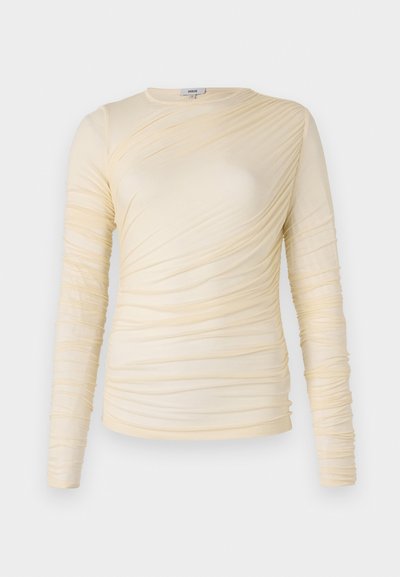 Top de manga larga crema, presenta una textura fruncida con una silueta ligeramente ajustada. Tejido suave con un escote redondo y costuras lisas.