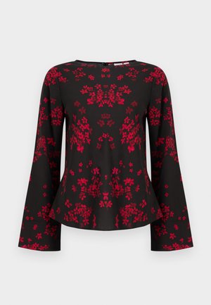 Blouse noire à manches longues avec motif floral rouge, encolure ronde, manches et ourlet légèrement évasés.