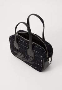 Μαύρη τσάντα χειρός από tweed με δερμάτινες λεπτομέρειες, διπλές χειρολαβές στην επάνω πλευρά, κλείσιμο με φερμουάρ και διακοσμητική γραφή μπροστά. Συμπαγής και δομημένος σχεδιασμός.