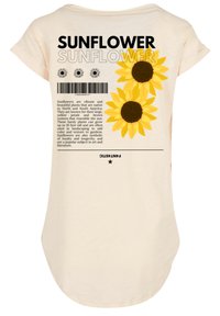 Light beige T-shirt with a rounded hem, featuring yellow sunflower graphics and black text on the back with a barcode and descriptive text.