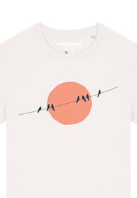 Weißes T-Shirt mit rundem Halsausschnitt, das eine Grafik von fünf schwarzen Vögeln auf einer Drahtlinie vor einem großen orangefarbenen Kreis zeigt.