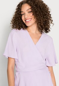 Vestido envolvente em lavanda claro com mangas curtas em floco, decote em V e um tecido texturizado, ajustado na cintura com um detalhe de laço.