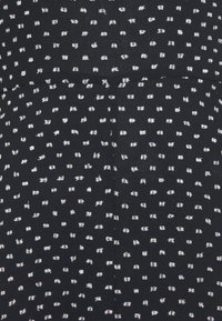 Černá tkanina s rozptýleným vzorem bílých teček. Měkká textura s mírným leskem a upraveným povrchem, s rovnými liniemi.