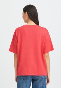 T-shirt surdimensionné corail à manches courtes et encolure ronde, fabriqué en tissu doux, associé à un jean denim bleu.