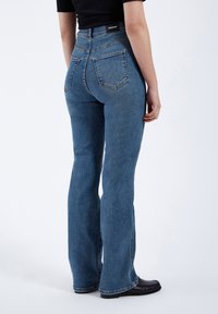 Hög midja blå denim jeans med utsvängda ben, två bakfickor och en ren finish. Materialet har en klassisk struktur och en svag blekning.