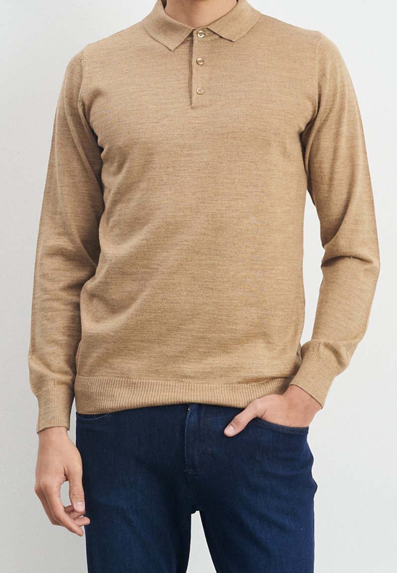 Beige polo shirt met lange mouwen, gemaakt van een gestructureerde brei, met een drieknoopsluiting en ribgebreide manchetten en zoom, gecombineerd met donkerblauwe jeans.