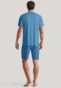 Blauwe kortemouwen shirt van soepel materiaal, gecombineerd met bijpassende gestreepte shorts in een donkerdere blauwe kleur, met een ontspannen pasvorm en casual stijl.