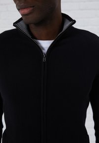 Marinblå zip-up tröja med hög krage och grå inredning. Har en mjuk yta, elegant design och en metalldragkedja.