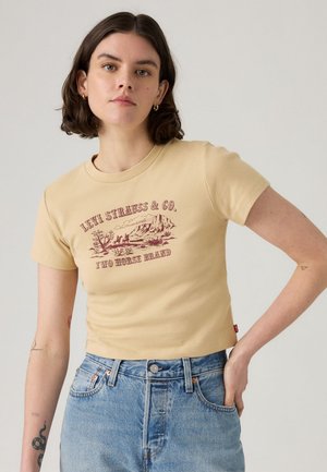 Beige bomulls t-shirt med tryck i vinröd som säger "LEVI STRAUSS & CO. TWO HORSE BRAND." Kort ärm och rundad halsringning.