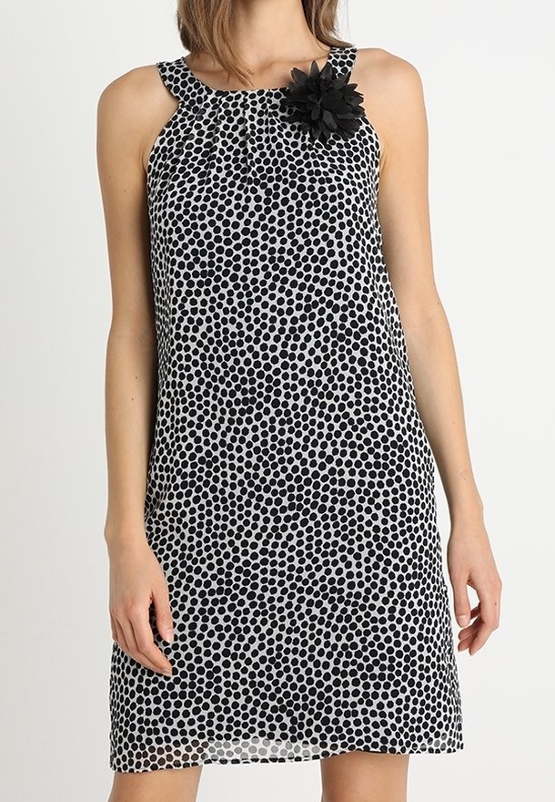 Mustavalkoinen pilkullinen mekko pyöreällä pääntiellä, kukkakoriste olkapäällä ja rento siluetti. Silkkinen, kevyt kangas.