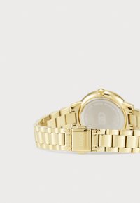 Gold-toned metal watch with a linked bracelet, round case, and a clasp closure. Back features markings and a polished finish.