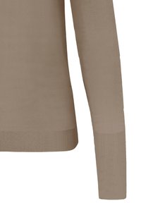 Haut en maille beige à manches longues avec poignets et taille côtelés, montrant la partie inférieure du torse et le bras droit.