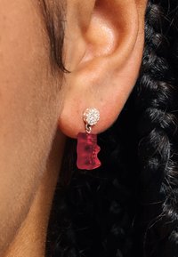 Rote Ohrringe in Form von Gummibärchen mit einem durchscheinenden Design und einem kleinen, funkelnden, runden Stecker als Befestigung.