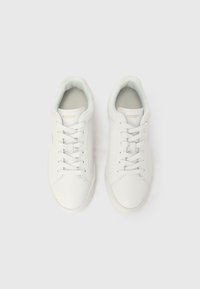 Adidași din piele albă cu o textură netedă, cu vârf rotund și șireturi plate. Prezintă un branding subtil pe limbă și un guler matlasat.