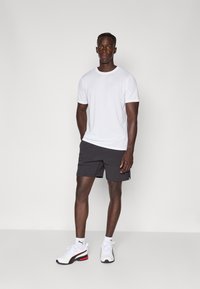 Hvit kortermet t-skjorte, svarte shorts og hvite joggesko med røde detaljer. Enkelt design, komfortabel passform og sporty utseende.