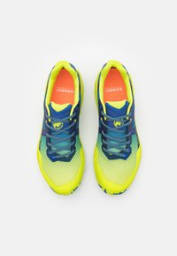 Helle gelbe Sportschuhe mit blauen Akzenten; Obermaterial aus Mesh, strukturierte Sohle und gemusterte Details an den Seiten. Mit kontrastierenden Schnürsenkeln und Logo.