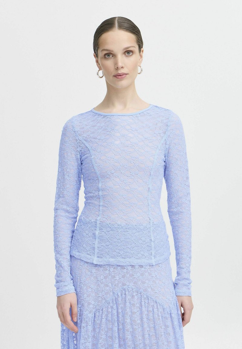 Top a maniche lunghe in pizzo azzurro chiaro con design aderente, delicato motivo floreale e scollatura rotonda, abbinato a una gonna in pizzo coordinata.