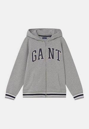 Sweat à capuche gris à fermeture éclair avec poches frontales, poignets et ourlet rayés bleu marine et blanc, et grand logo "GANT" sur la poitrine.