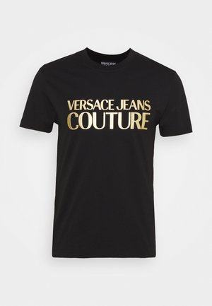 Zwarte katoenen t-shirt met een grote gouden metallic print van "VERSACE JEANS COUTURE" op de voorkant. Korte mouwen en standaard ronde hals.