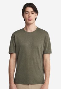 Olivgrön kortärmad T-shirt i mjukt, strukturerat tyg, med rund halsringning och avslappnad passform. Inga synliga logotyper.