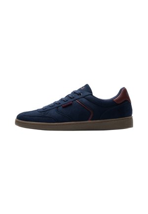 Navyblauwe casual sneaker met bruine zool, veters aan de voorkant en een bruin hielaccent, zijaanzicht op een witte achtergrond.