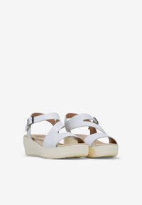 Sandali wedges bianchi con cinturini incrociati, fibbia regolabile e una morbida soletta imbottita. Texture liscia con finitura opaca.