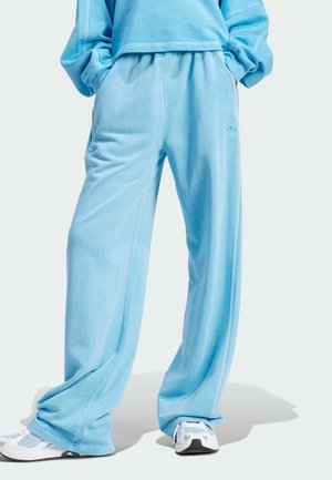 Loose light blue sweatpants with hands in pockets, paired with white and light blue sneakers, shown from waist to feet.