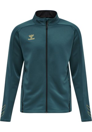 Teal zip-up jack met een zwarte binnenkraag, gouden logo en zijzakken met rits. Kenmerkend zijn de schuine gouden strepen op de mouwen.