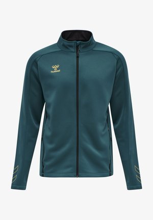 Türkisfarbene Zip-Jacke mit schwarzem Innenkragen, goldenem Logo und seitlichen Reißverschlusstaschen. Verfügt über schräg verlaufende goldene Streifen an den Ärmeln.