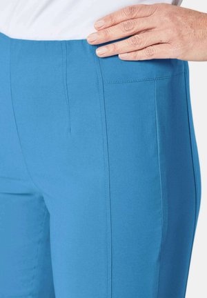 Pantalons bleus extensibles avec une texture lisse, présentant un design ajusté et une couture latérale. La ceinture est simple et ajustée. Pas de poches visibles.