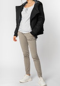 Czarna ocieplana kurtka z kapturem, szara koszulka henley, beżowe spodnie slim-fit oraz białe trampki. Charakterystyczna pikowana podszewka wewnętrzna.