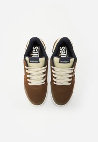 Bruna mocka sneakers med krämfärgade snören och plös, med en mörkblå foder och texturerad sula. Etnies-logotyp på sidan.