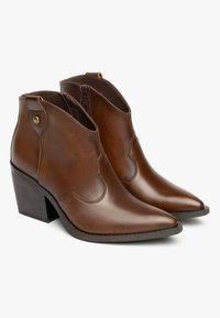 Botas de tobillo de cuero marrón con punteras afiladas, laterales bajos y un tacón cuadrado. Presentan costuras sutiles y un cierre de cremallera en un lado.