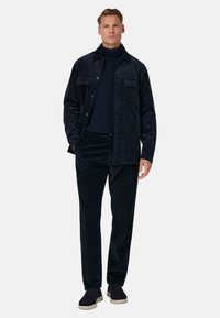 Jūras flotes kordūra jaka ar divām krūšu kabatām, savienota ar atbilstošām biksēm. Valkāta virs jūras flotes augsto kaklu, papildināta ar tumšām mokasīnām.