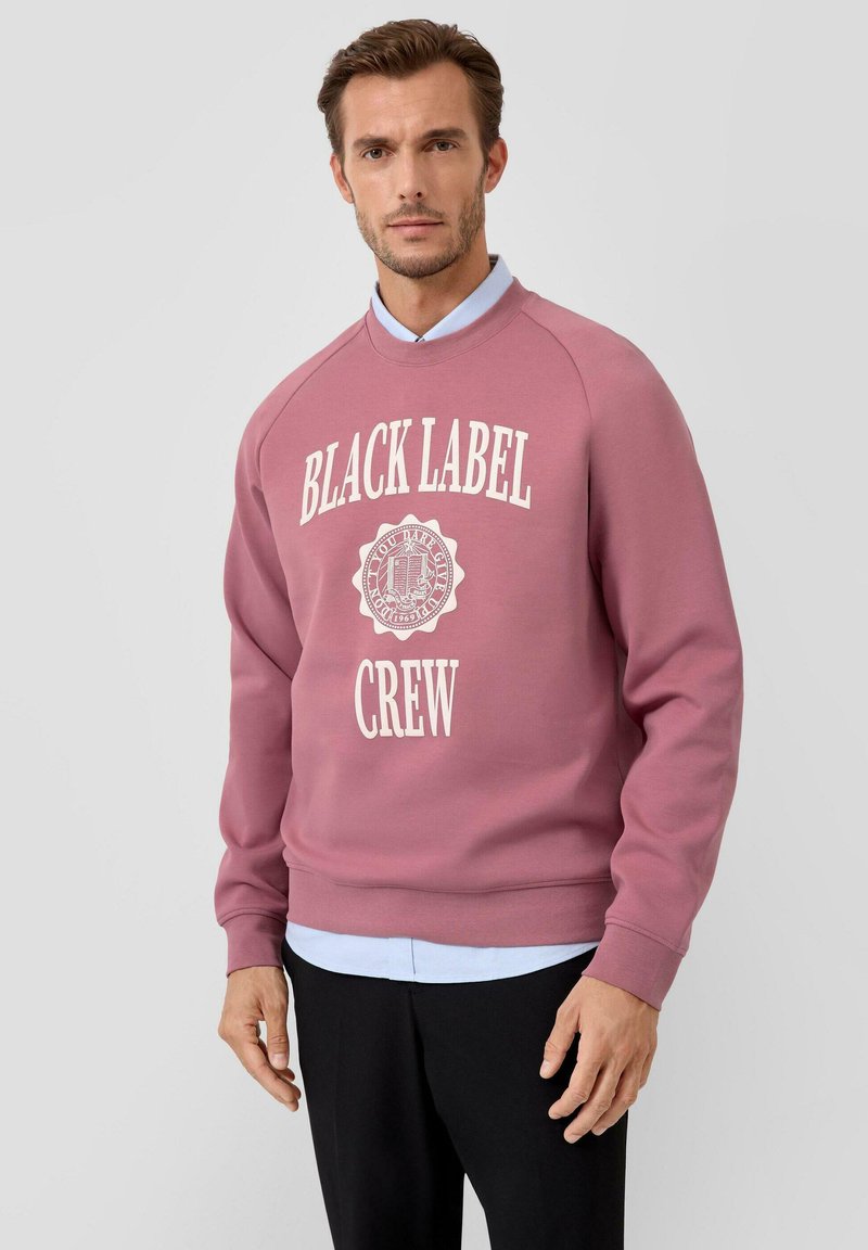 Rosa Sweatshirt mit weißem Aufdruck "BLACK LABEL CREW". Verfügt über einen Rundhalsausschnitt und gerippte Bündchen, getragen über einem hellblauen Hemd mit Kragen.