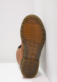 Bota marrón con suela de goma, upper de cuero texturizado, con detalles de costura y una suela con tacos para mayor agarre.