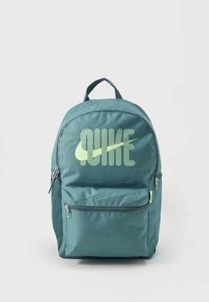 Sac à dos turquoise avec poche avant zippée et logo « NIKE » stylisé en vert clair ainsi qu'un swoosh sur le panneau avant sur fond blanc.