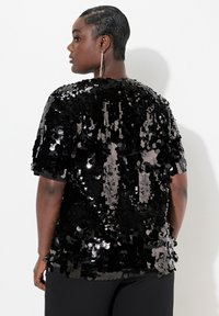 Top corto a maniche corte nero con un fit morbido, caratterizzato da paillettes rotonde lucide che coprono l'intera superficie e una texture morbida.