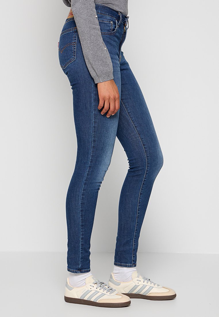 Schmale blaue Jeans aus Denim mit einem mittelhohen Bund, kontrastierenden Nähten und einem klassischen Fünf-Taschen-Design.