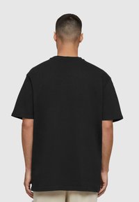 Sort bomulds t-shirt med rund hals, korte ærmer og en afslappet pasform, vist fra ryggen med en glat tekstur.