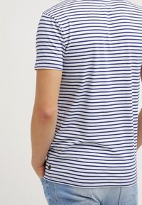 Kurze Ärmel T-Shirt in Weiß mit navyblauen horizontalen Streifen, mit rundem Halsausschnitt und kleinem Logo am Saum. Aus Baumwollmaterial.