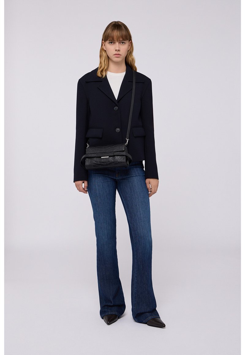 Blazer navy con chiusura a bottoni, tasche frontali; abbinato a jeans blu a palazzo e una borsa a tracolla nera testurizzata, con chiusura magnetica.