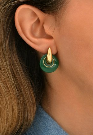 Boucles d'oreilles dorées et vertes avec une base circulaire verte et un accent doré dessus, mettant en valeur un design épuré et une finition polie.
