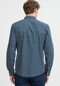 Camicia a maniche lunghe blu navy con un motivo a foglia bianca, colletto a bottoni, design aderente con polsini a bottoni e orlo curvo.