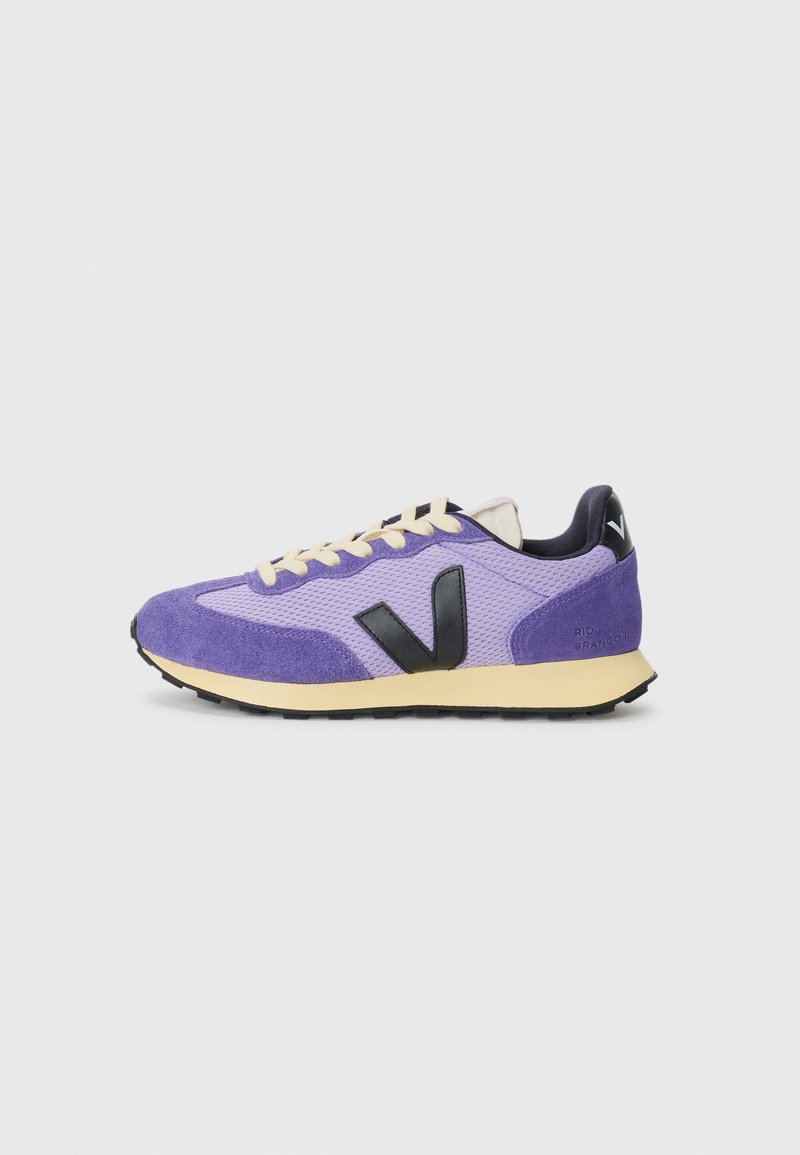 Purple sneaker with suede and mesh material, black logo detail, cream laces, and a yellow sole. Features textured surface and contrasting accents.