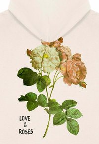Felpa bianca con un design floreale che presenta rose rosa e crema. Il testo recita "AMORE & ROSE," con foglie verdi che accentuano la stampa.