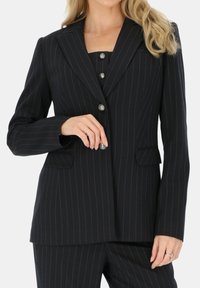 Granatowa marynarka w paski z klapami, srebrnymi guzikami i dwiema przednimi kieszeniami. Poliester o gładkiej fakturze.