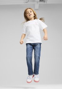 Hvid bomulds t-shirt med korte ærmer, blå denim jeans og hvide sneakers med en lyserød sål, udsmykket med et Hello Kitty design.