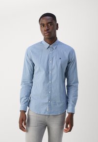 Blue and white checkered long-sleeve shirt with button-down collar, featuring a small embroidered logo on the chest and a rounded hem.