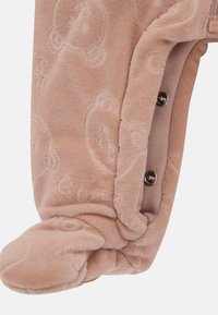 Mitaine pour bébé douce en rose pâle avec des motifs de ours en relief et des boutons-pression sur le côté pour un fermeture sécurisée.